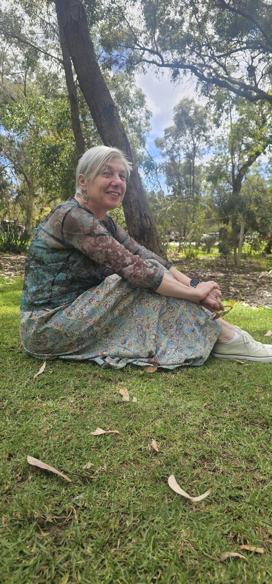 Woman sitting in a park smiling gently, reflecting on the first signs of coming back to life after a difficult season. Woman sitting in a park smiling gently, reflecting on the first signs of coming back to life after a difficult season.